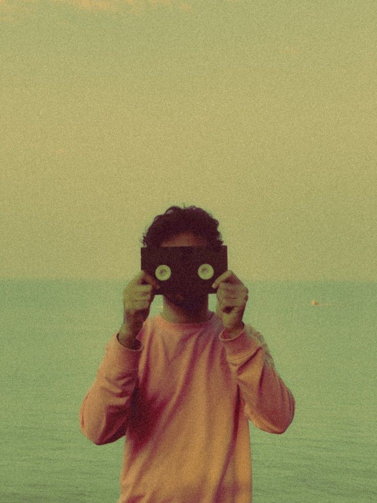 Person holding a viewfinder camera up to their face at the ocean